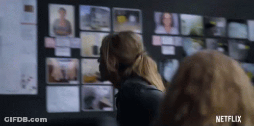 A Woman Is Standing In Front Of A Wall With Pictures On It And A Netflix Logo In The Corner . GIF