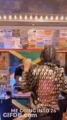 A Woman Is Standing In Front Of A Wall With Posters On It . GIF