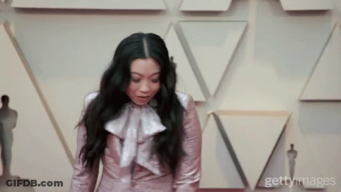 A Woman Is Standing In Front Of A Wall With Triangles On It GIF