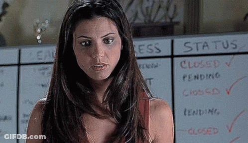 A Woman Is Standing In Front Of A White Board With The Word Status Written On It . GIF
