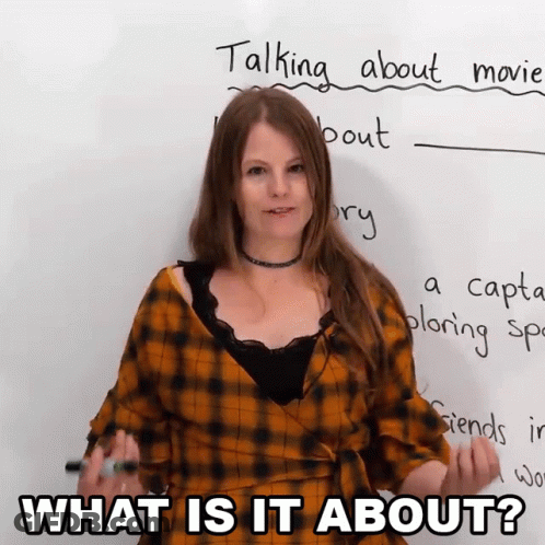 A Woman Is Standing In Front Of A White Board With The Words What Is It About Written On It GIF