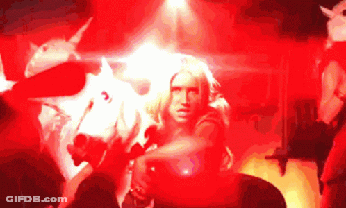 A Woman Is Standing In Front Of A White Unicorn GIF