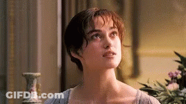 A Woman Is Standing In Front Of A Window In A Room With A Vase In The Background . GIF