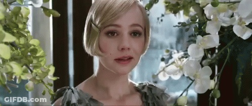 A Woman Is Standing In Front Of A Window Surrounded By Flowers And Looking At The Camera . GIF