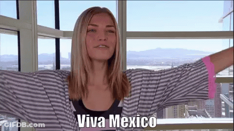 A Woman Is Standing In Front Of A Window With Her Arms Outstretched And The Words Viva Mexico On Her Face . GIF