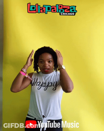A Woman Is Standing In Front Of A Yellow Background That Says ' Lolapaloza Chicago ' On It GIF