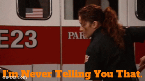 A Woman Is Standing In Front Of An Ambulance With The Number 23 On It GIF