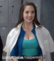A Woman Is Standing In Front Of Lockers And Smiling While Asking What Is Happening . GIF