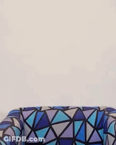 A Woman Is Standing Next To A Colorful Couch With A Geometric Pattern . GIF