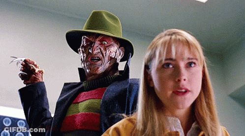 A Woman Is Standing Next To A Freddy Krueger Doll GIF