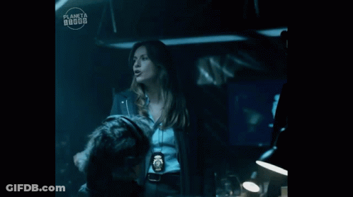 A Woman Is Standing Next To A Man In A Dark Room With A Planeta Logo In The Corner . GIF