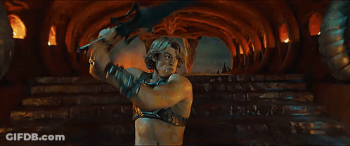 A Woman Is Standing Next To A Man In A Dark Room With A Sword . GIF