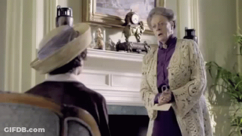 A Woman Is Standing Next To A Man In A Living Room Holding A Piece Of Paper . GIF
