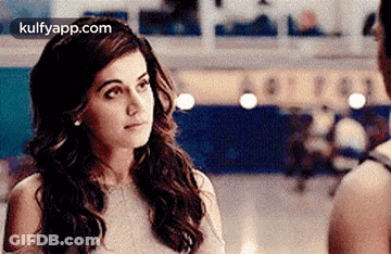 A Woman Is Standing Next To A Man In A Room Looking At Him . GIF