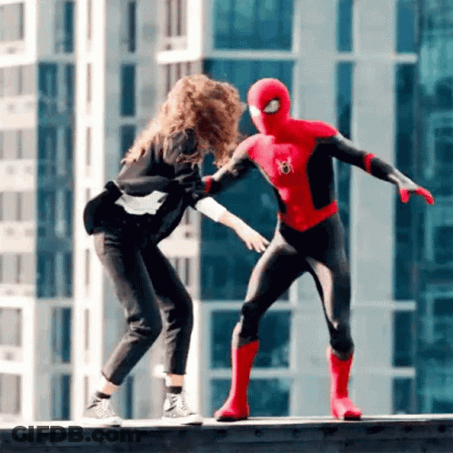 A Woman Is Standing Next To A Man In A Spiderman Costume On A Ledge . GIF