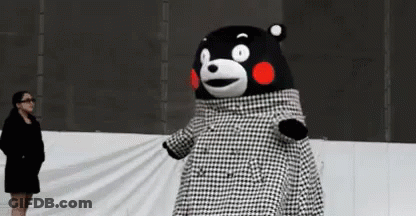 A Woman Is Standing Next To A Teddy Bear Wearing A Black And White Plaid Coat . GIF