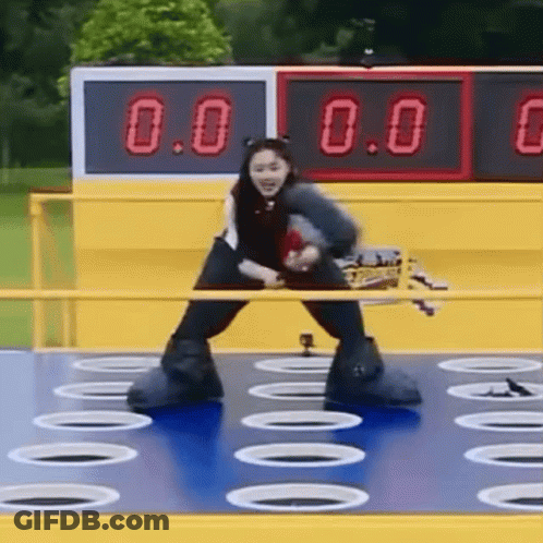 A Woman Is Standing On A Blue Surface With Holes In It And A Scoreboard In The Background . GIF