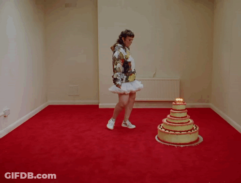 A Woman Is Standing On A Cake That Has Candles On It GIF