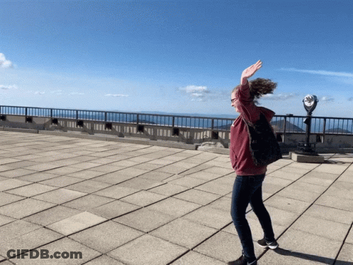 A Woman Is Standing On A Rooftop With Her Arms Outstretched GIF