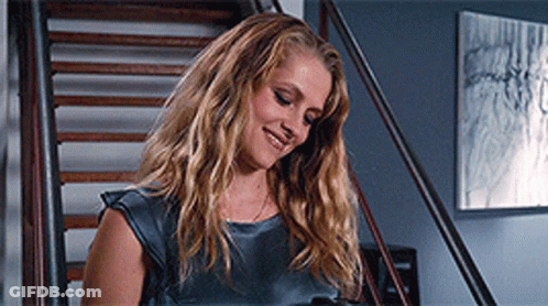 A Woman Is Standing On A Set Of Stairs And Smiling GIF