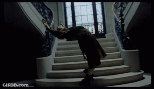 A Woman Is Standing On A Set Of Stairs With Her Arms Outstretched GIF