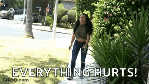 A Woman Is Standing On A Sidewalk With The Words `` Everything Hurts '' Written On The Ground . GIF