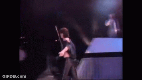 A Woman Is Standing On A Stage Holding A Microphone . GIF