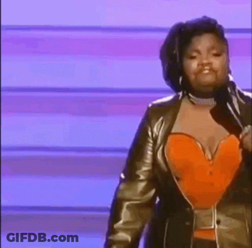 A Woman Is Standing On A Stage Holding A Microphone And Wearing An Orange Corset . GIF
