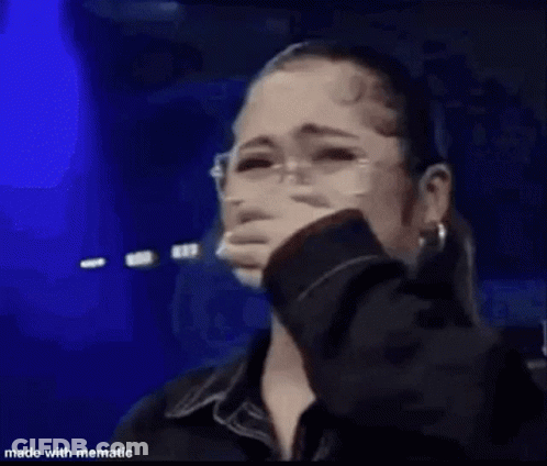 A Woman Is Standing On A Stage Holding A Microphone . GIF