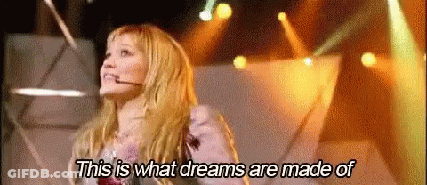 A Woman Is Standing On A Stage With A Microphone In Her Mouth . GIF