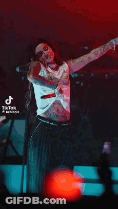 A Woman Is Standing On A Stage With Her Arms Outstretched While Singing Into A Microphone . GIF