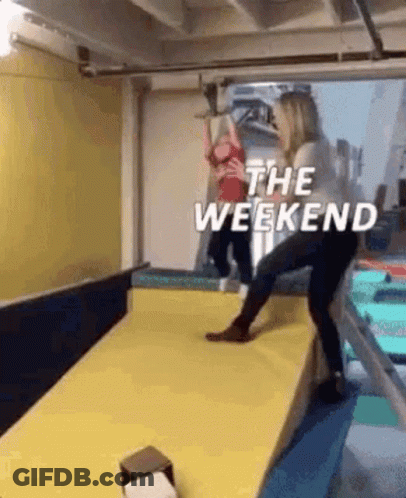 A Woman Is Standing On A Yellow Mat In A Gym With A Child . GIF