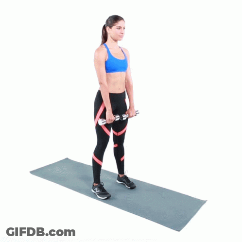 A Woman Is Standing On A Yoga Mat Holding Two Dumbbells In Her Hands GIF