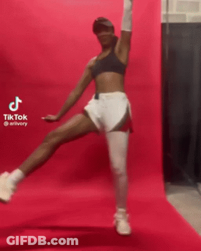 A Woman Is Standing On One Leg In Front Of A Pink Wall And A Pink Background . GIF