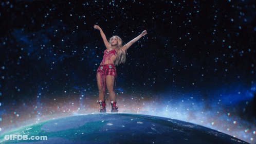A Woman Is Standing On Top Of A Globe With Her Arms In The Air GIF