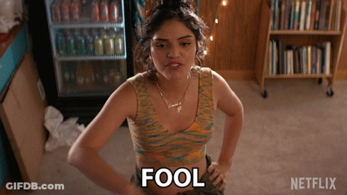 A Woman Is Standing With Her Hands On Her Hips And The Word Fool Is On The Floor GIF