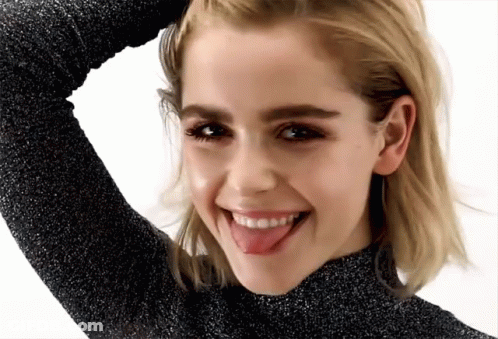 A Woman Is Sticking Her Tongue Out And Smiling GIF