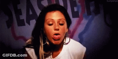A Woman Is Sticking Her Tongue Out In Front Of A Sign That Says Pleasure Beach . GIF