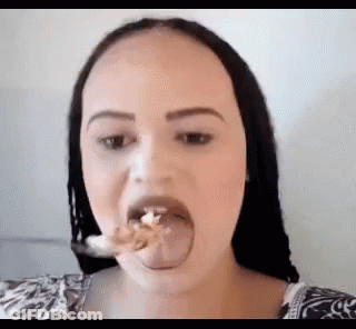 A Woman Is Sticking Her Tongue Out While Eating A Piece Of Food With A Spoon . GIF