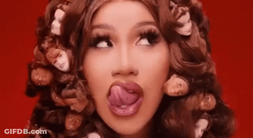 A Woman Is Sticking Her Tongue Out While Wearing A Wig With Heads On It . GIF