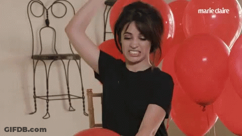 A Woman Is Surrounded By Red Balloons With Marie Claire Written On The Balloons GIF