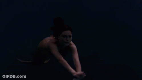 A Woman Is Swimming In A Body Of Water GIF