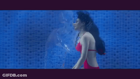 A Woman Is Swimming Underwater In A Pool And Looking At Her Reflection . GIF