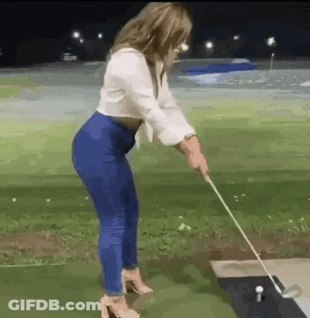 A Woman Is Swinging A Golf Club At A Golf Ball . GIF