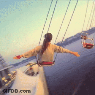 A Woman Is Swinging On A Merry Go Round At A Carnival GIF