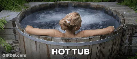 A Woman Is Taking A Bath In A Wooden Tub With The Words Hot Tub Below Her GIF