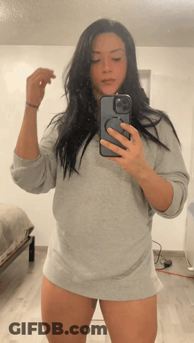 A Woman Is Taking A Picture Of Herself In A Mirror GIF