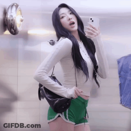 A Woman Is Taking A Picture Of Herself In A Mirror GIF