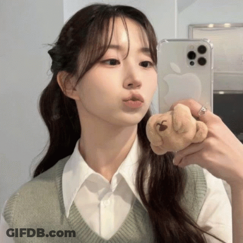 A Woman Is Taking A Picture Of Herself In A Mirror With An Apple Phone GIF
