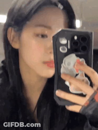A Woman Is Taking A Picture Of Herself In The Mirror GIF
